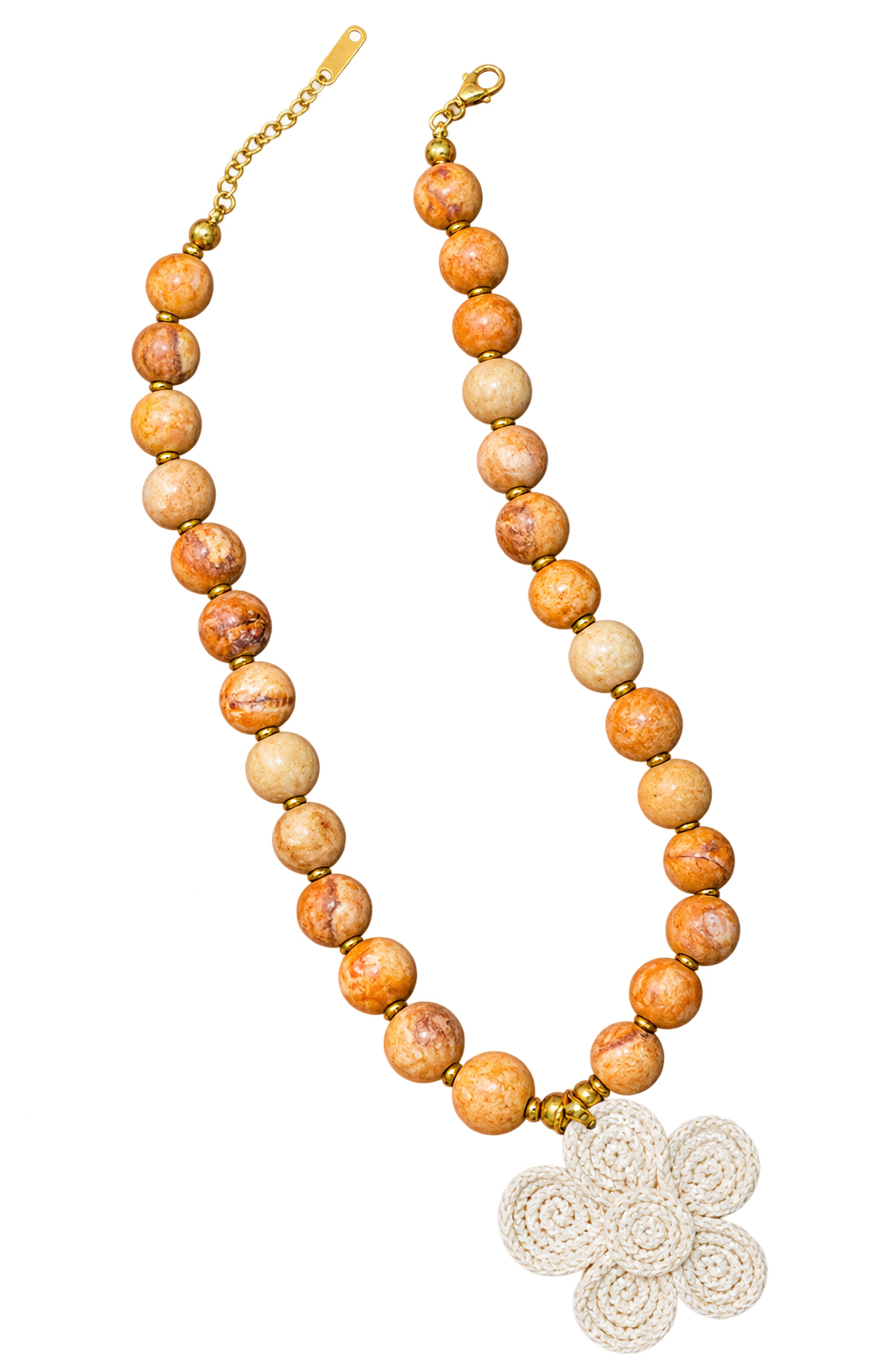 A beaded necklace featuring round, marbled orange and beige stone beads separated by small gold spacer beads, with a gold clasp and extender chain on one side and a white crocheted flower-shaped charm on the other, displayed on a solid white background.